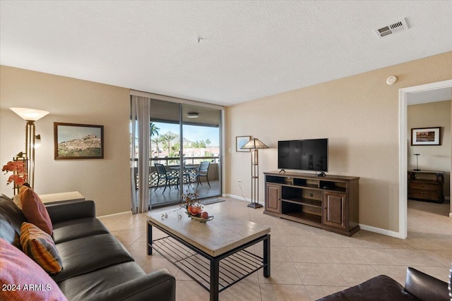 tiled living room featuring a textured ceiling and a wall of windows