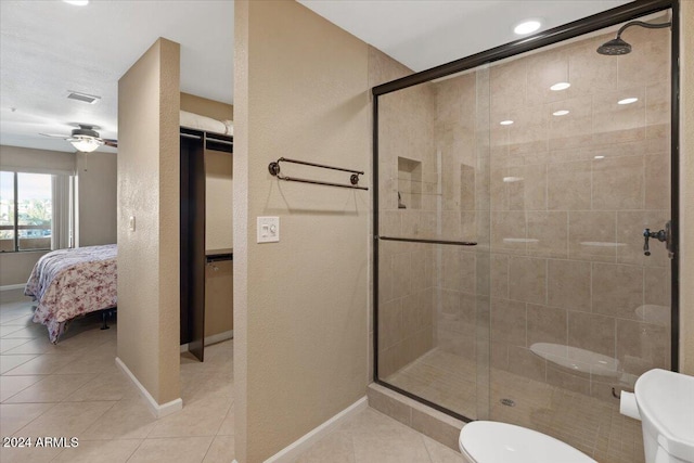 bathroom featuring tile patterned flooring, toilet, and a shower with door