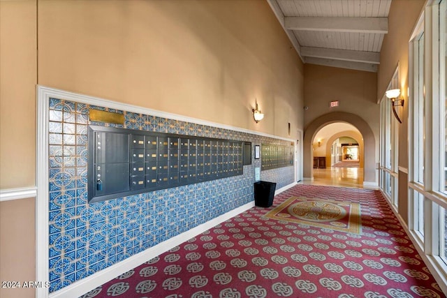 hall with carpet, wood ceiling, beam ceiling, high vaulted ceiling, and a mail area