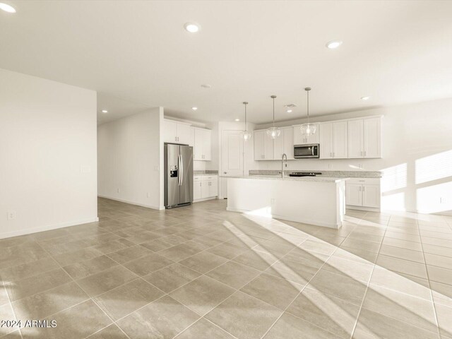 kitchen featuring light tile patterned floors, an island with sink, pendant lighting, white cabinets, and appliances with stainless steel finishes