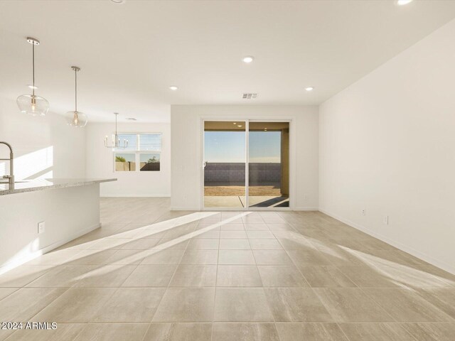 spare room featuring light tile patterned floors and a notable chandelier