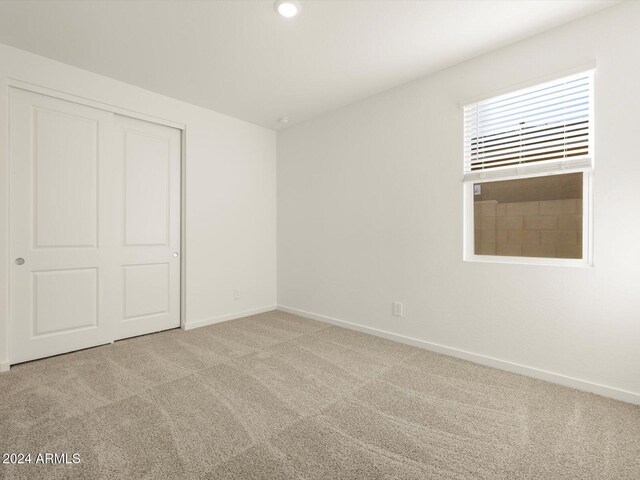 unfurnished bedroom with light carpet and a closet