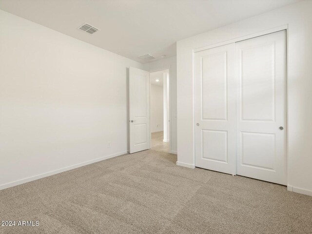 unfurnished bedroom featuring light colored carpet and a closet