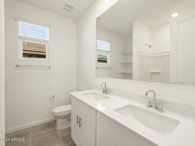 bathroom with tile patterned floors, vanity, toilet, and a wealth of natural light