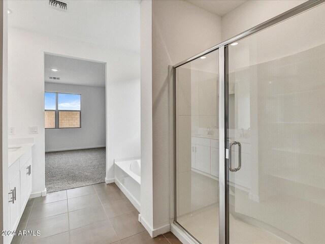 bathroom featuring tile patterned flooring, vanity, and plus walk in shower