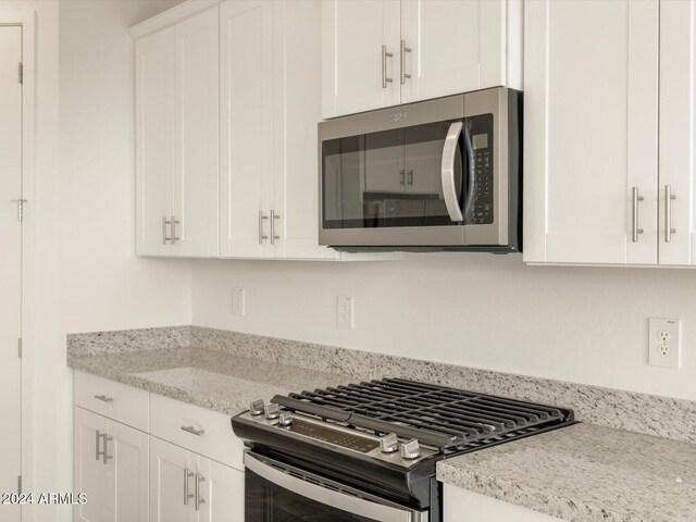 kitchen with light stone counters, white cabinetry, and appliances with stainless steel finishes