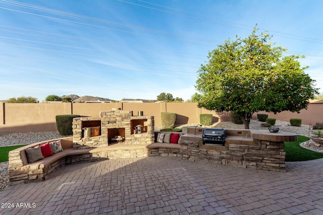 view of patio / terrace featuring an outdoor stone fireplace, area for grilling, and an outdoor kitchen