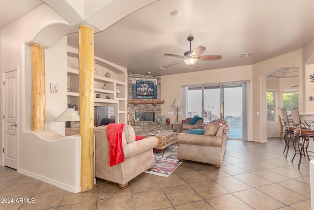 living room with a fireplace, built in shelves, tile patterned flooring, and ceiling fan