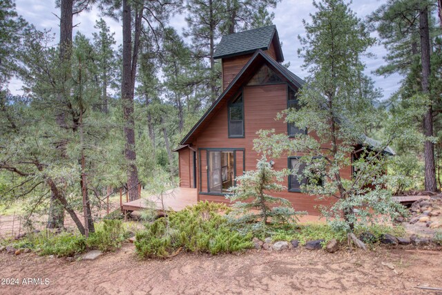 exterior space with a shingled roof and a wooden deck