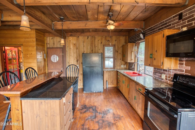 kitchen with black appliances, wood finished floors, a sink, and beamed ceiling