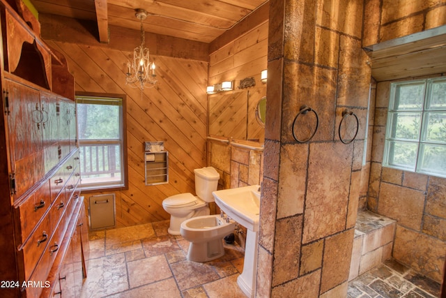 full bathroom featuring a chandelier, toilet, wood ceiling, a bidet, and stone tile flooring