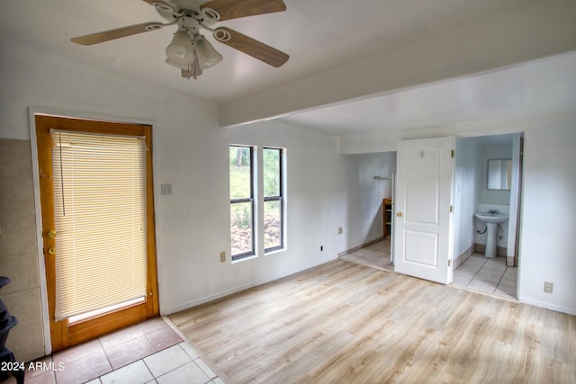 unfurnished room with light tile patterned floors, a sink, a ceiling fan, and baseboards