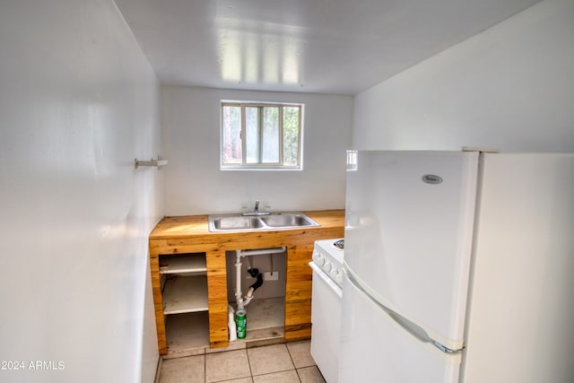 kitchen featuring white appliances, light tile patterned floors, and a sink