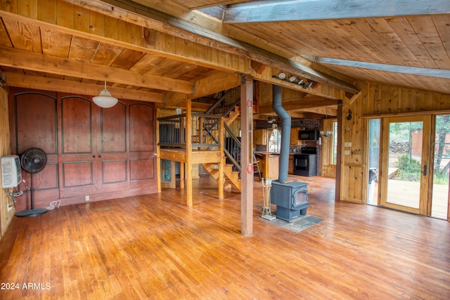 interior space featuring wooden ceiling, wooden walls, stairway, light wood finished floors, and a wood stove