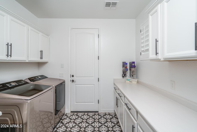 clothes washing area featuring cabinets and washing machine and clothes dryer