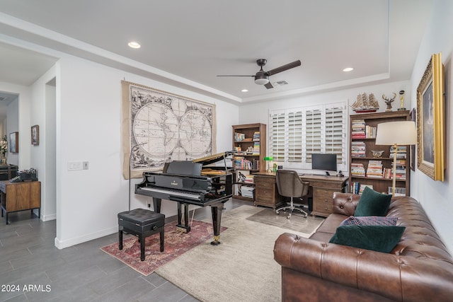 office space with a tray ceiling and ceiling fan