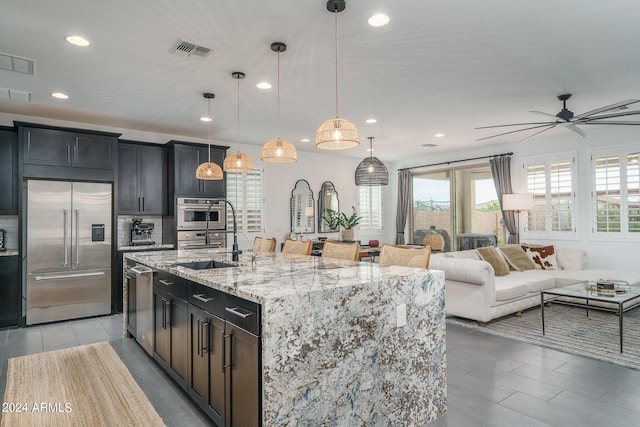 kitchen featuring a kitchen island with sink, hanging light fixtures, stainless steel appliances, and sink