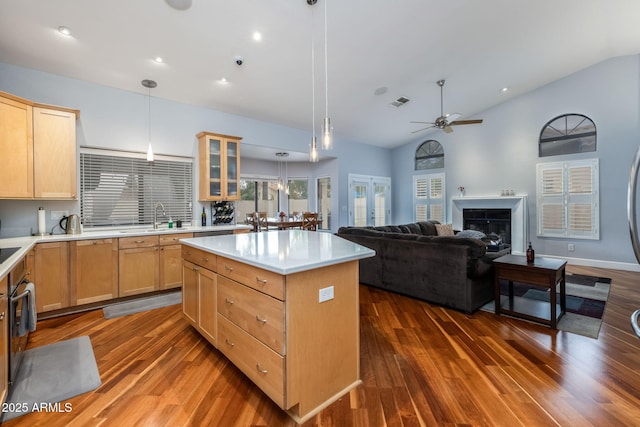 kitchen with a center island, ceiling fan, light brown cabinetry, light countertops, and a sink