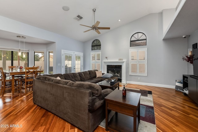 living area with visible vents, baseboards, a ceiling fan, and wood finished floors