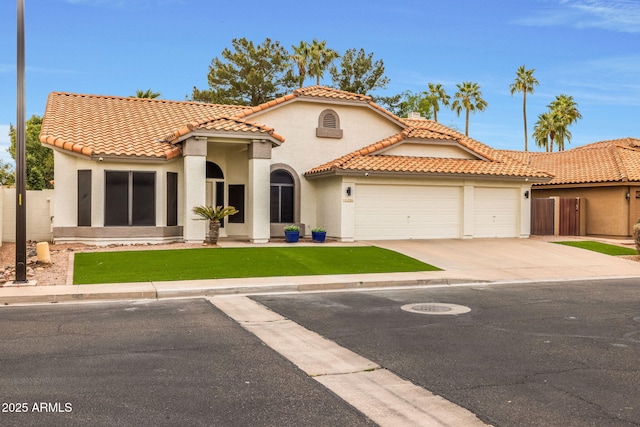 mediterranean / spanish-style home with stucco siding, a garage, driveway, and a tiled roof