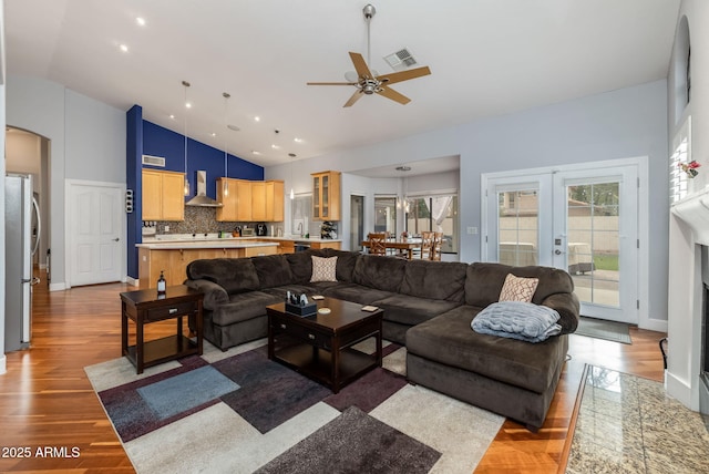 living area featuring visible vents, ceiling fan, french doors, wood finished floors, and high vaulted ceiling