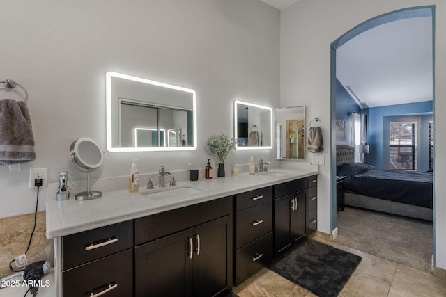 ensuite bathroom featuring a sink, connected bathroom, double vanity, and tile patterned flooring