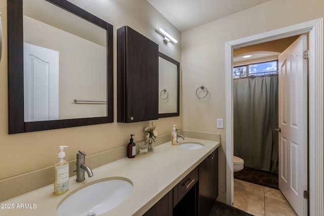 full bath featuring a shower with shower curtain, double vanity, toilet, and a sink