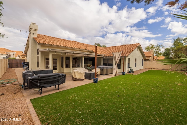 rear view of house featuring stucco siding, a tile roof, a fenced backyard, and a hot tub