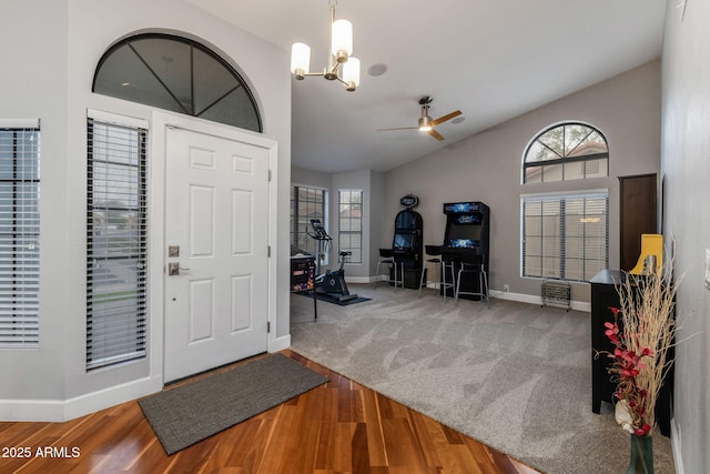 foyer entrance featuring ceiling fan with notable chandelier, baseboards, lofted ceiling, and wood finished floors