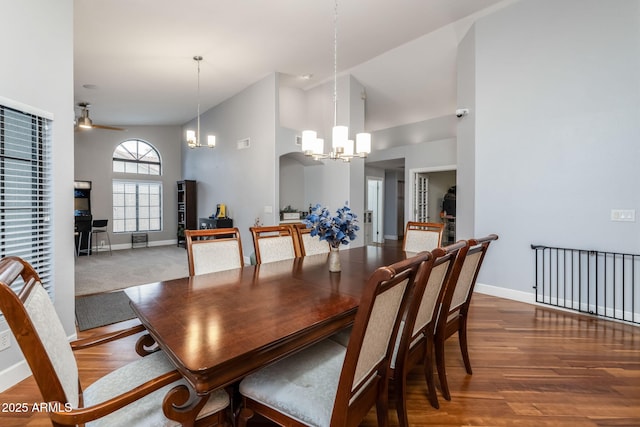 dining area featuring ceiling fan with notable chandelier, high vaulted ceiling, baseboards, and wood finished floors