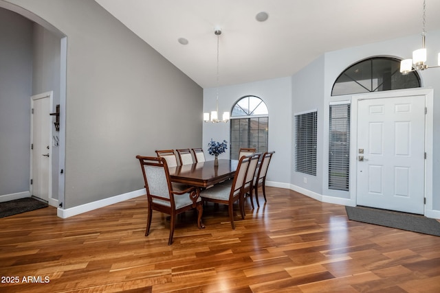 dining area with a notable chandelier, wood finished floors, and arched walkways