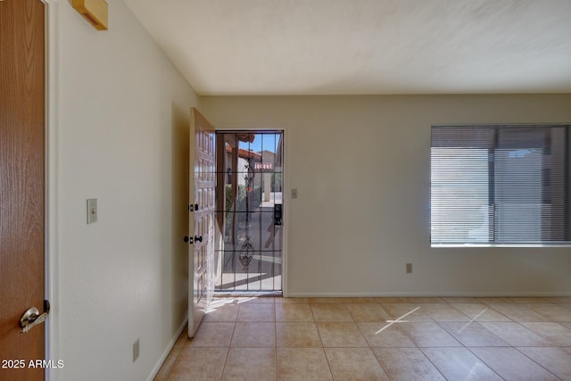 empty room featuring baseboards and light tile patterned floors