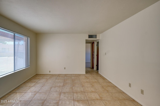 spare room with light tile patterned floors, visible vents, and baseboards