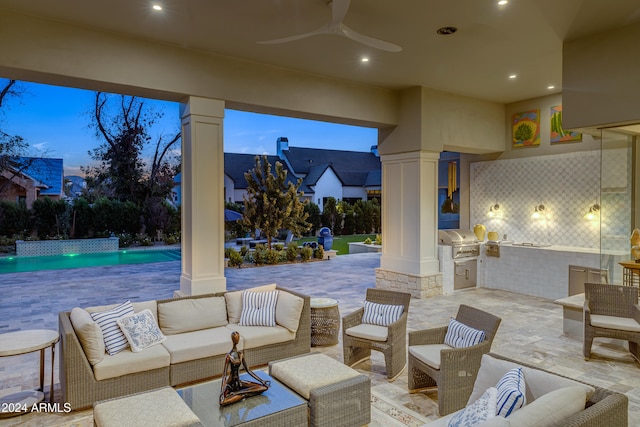 patio terrace at dusk featuring area for grilling, ceiling fan, and an outdoor hangout area