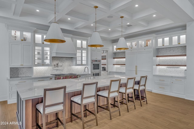 kitchen with a large island, beam ceiling, white cabinetry, and hanging light fixtures