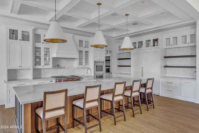 kitchen featuring white cabinetry, hanging light fixtures, and a large island with sink