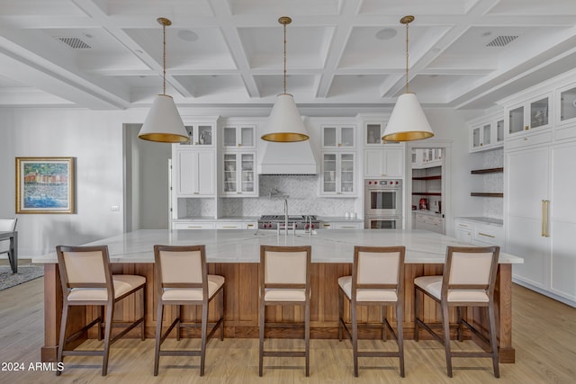 kitchen featuring a spacious island, light hardwood / wood-style flooring, white cabinetry, and hanging light fixtures