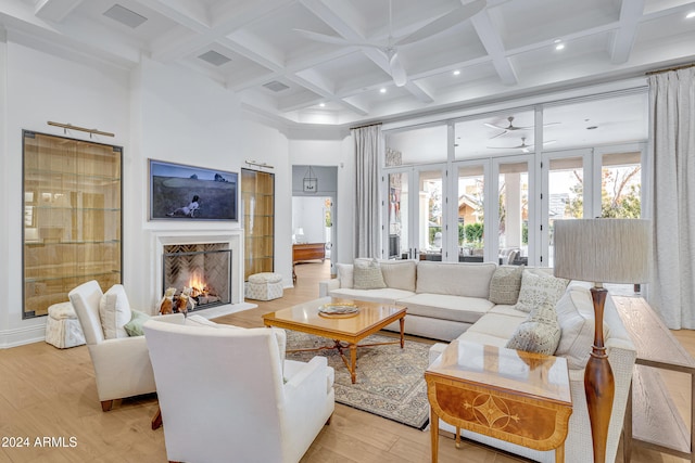 living room with light hardwood / wood-style floors, coffered ceiling, and beamed ceiling