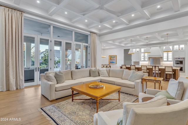 living room featuring french doors, beam ceiling, coffered ceiling, and light wood-type flooring