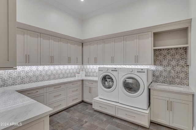 laundry area featuring sink, washer and clothes dryer, crown molding, and cabinets