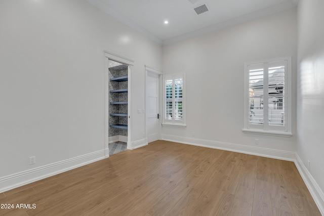 spare room with ornamental molding and light hardwood / wood-style flooring