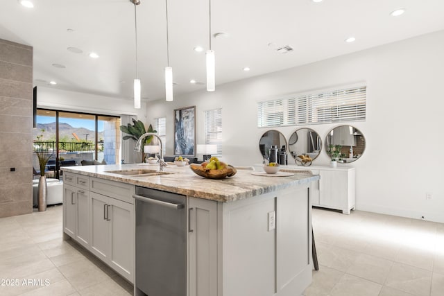 kitchen featuring sink, decorative light fixtures, light tile patterned floors, an island with sink, and light stone countertops