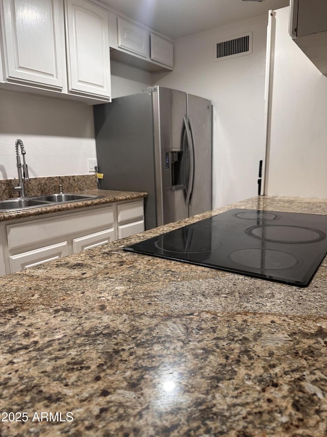 4232 W Citrus Way, Phoenix, AZ 85019 - kitchen with black electric cooktop, a sink, stainless steel fridge, white cabinetry, and dark stone countertops