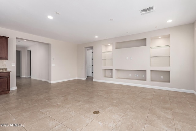 unfurnished living room with built in shelves and light tile patterned flooring