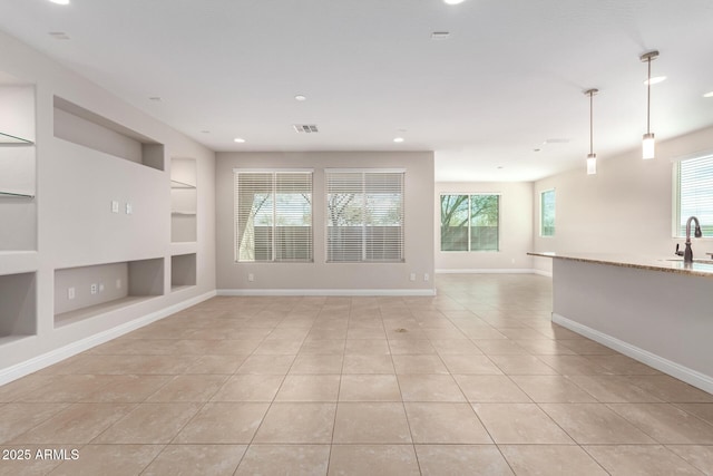 unfurnished living room featuring built in shelves, sink, and light tile patterned floors