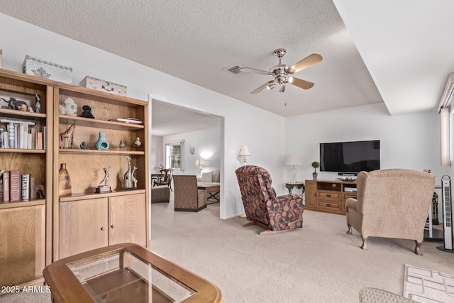 carpeted living room with a textured ceiling and a ceiling fan