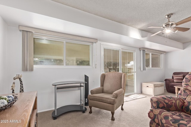 sitting room featuring baseboards, carpet, a ceiling fan, and a textured ceiling