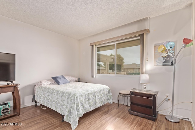 bedroom with a textured ceiling, wood finished floors, and baseboards