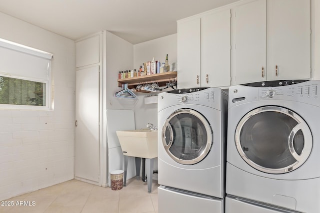 clothes washing area with light tile patterned floors, independent washer and dryer, and cabinet space