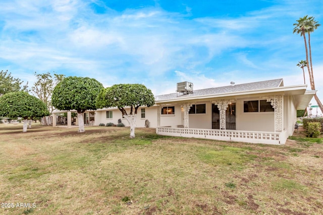 back of property featuring central air condition unit and a lawn